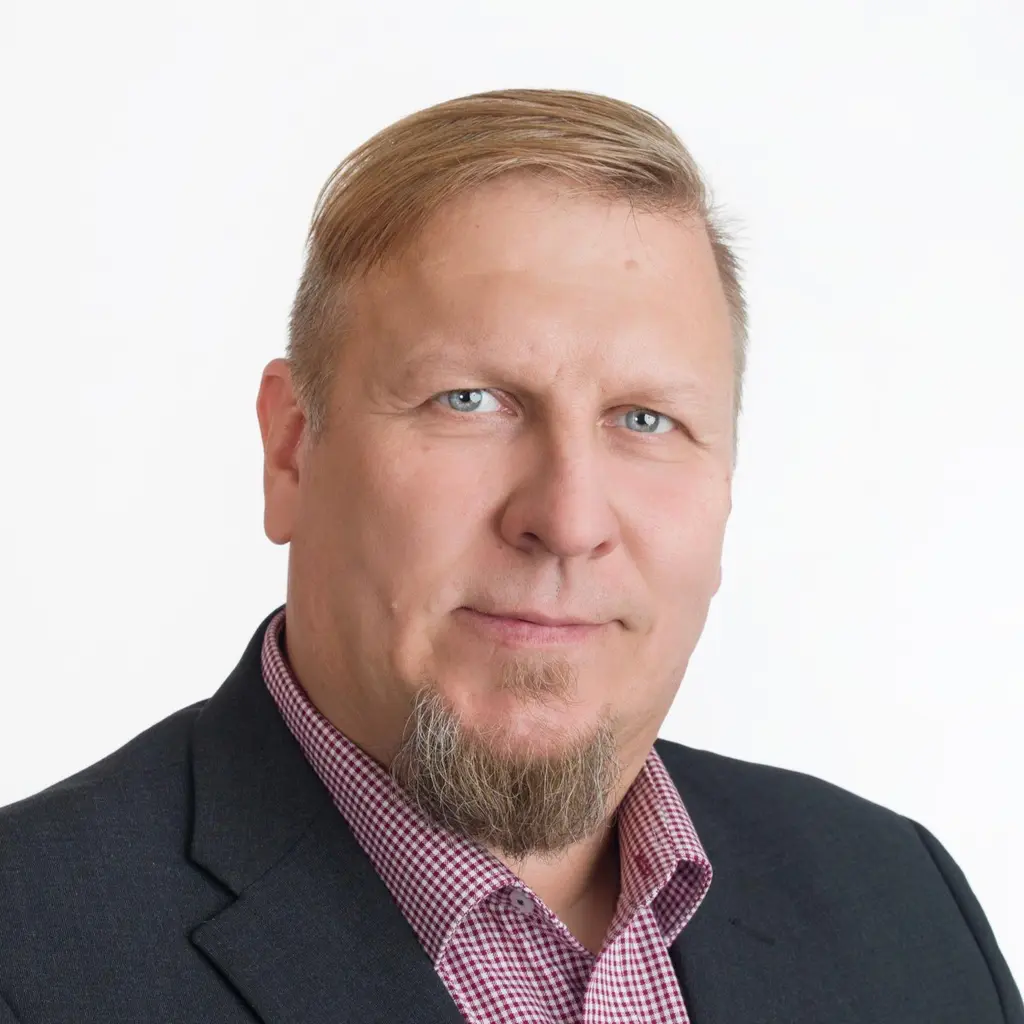 Mies katsoo kameraan hymyillen