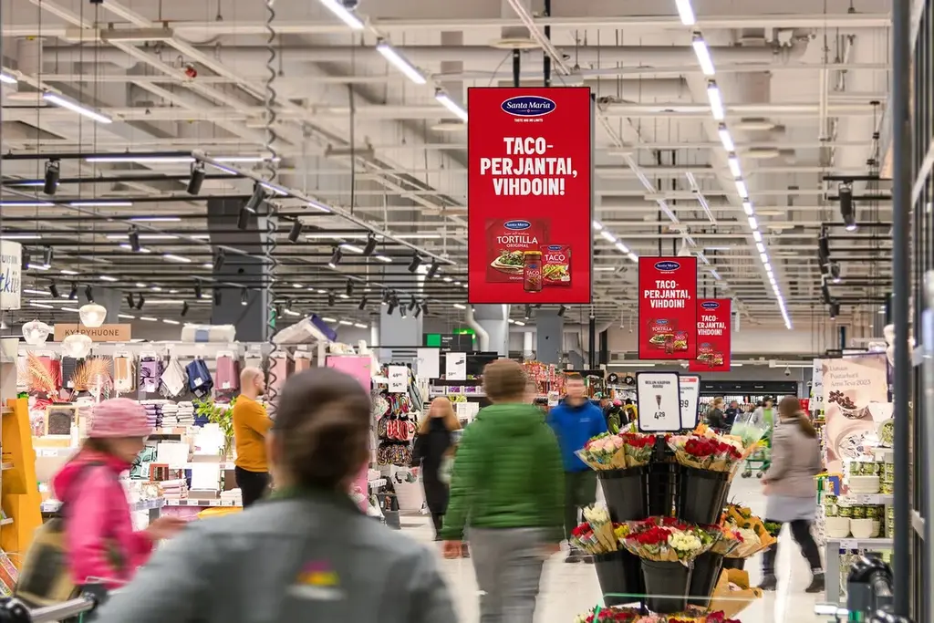 Kuva ruokakaupan käytävältä, jonka yläpuolella roikkuvat punaiset Santa Marian tacomainokset