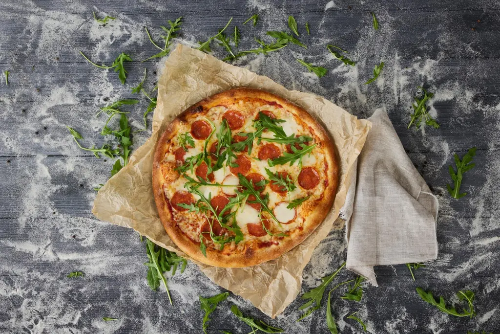 Rosson pepperonipizza ja rucolaa rouhealla alustalla.