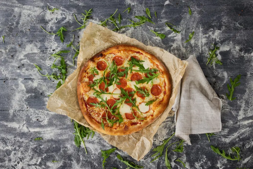Rosson pepperonipizza ja rucolaa rouhealla alustalla.