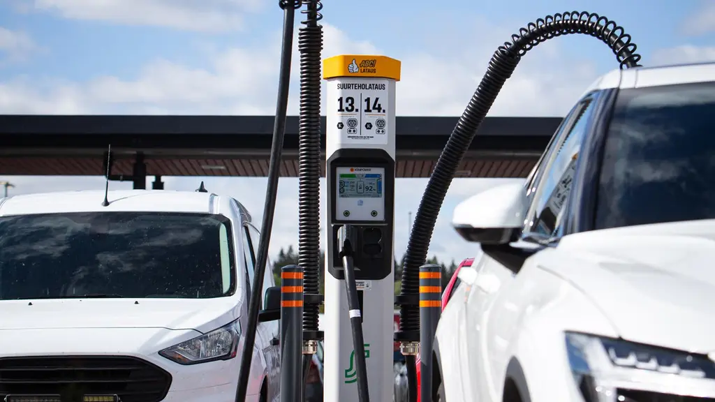 Kaksi valkoista autoa latauksessa ABC-asemalla.