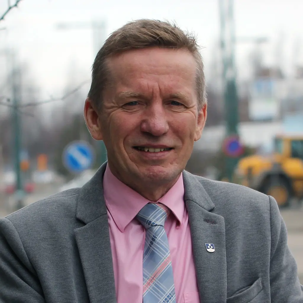 Mies katsoo kameraan hymyillen
