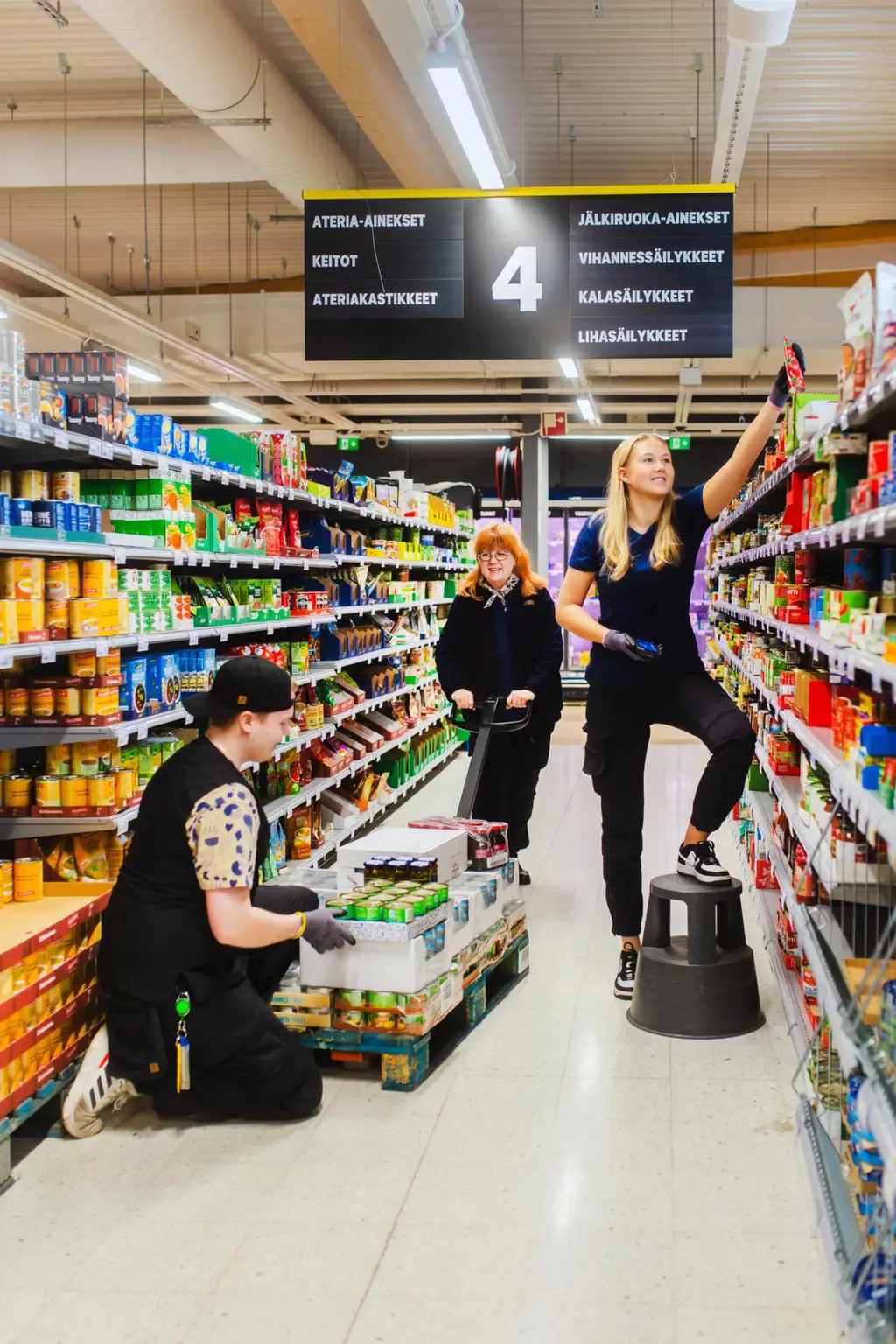 S-marketin käytävällä kolme myyjää työssä