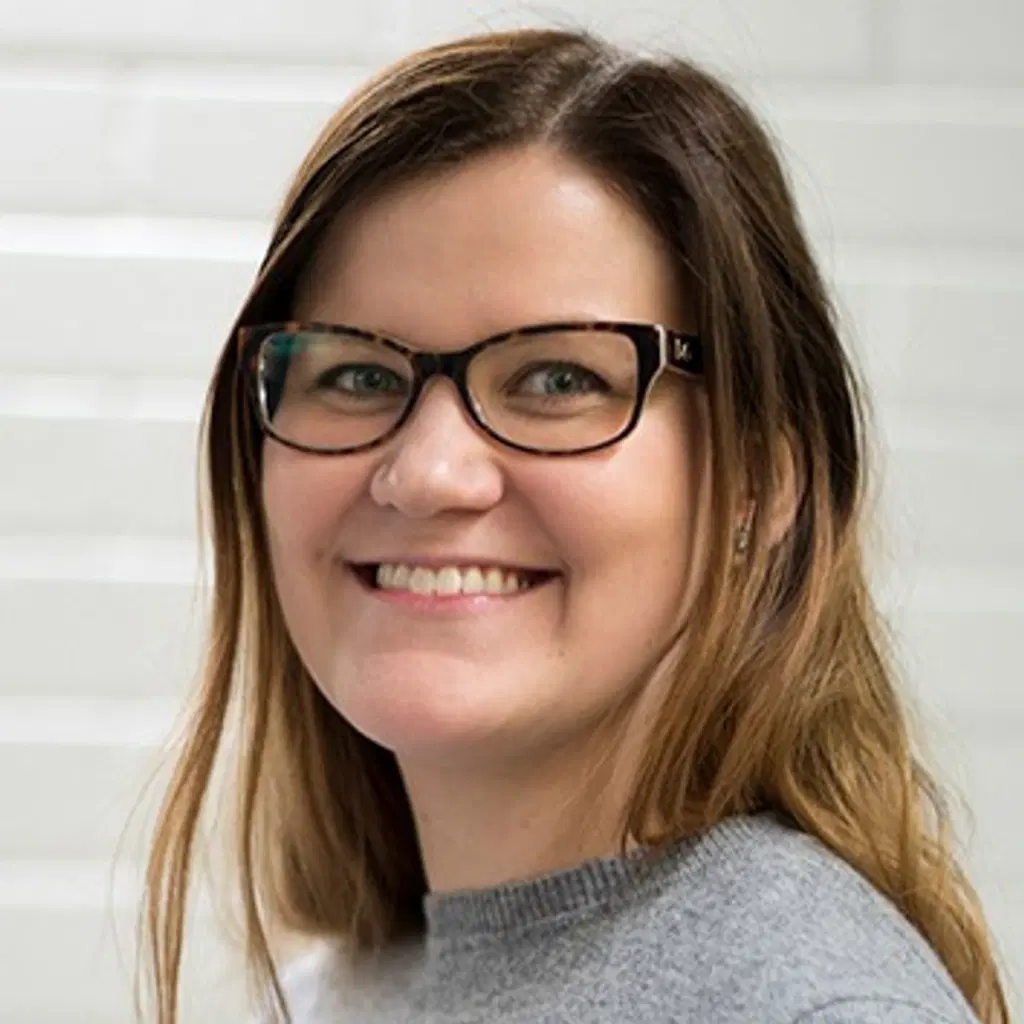 Nainen katsoo kameraan hymyillen