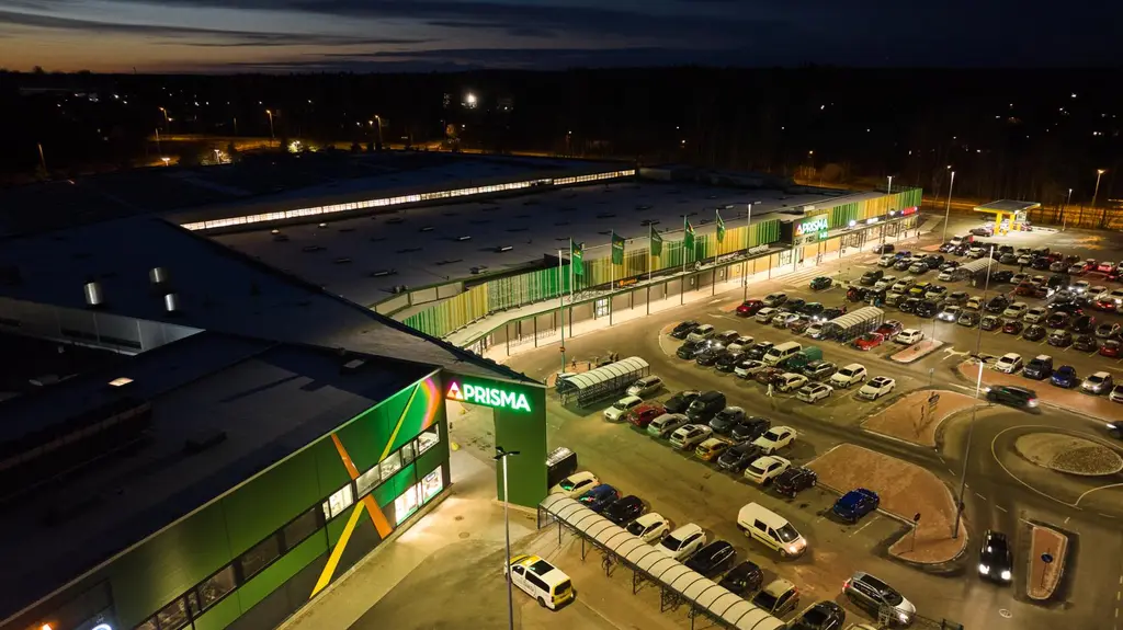 Öinen ilmakuva Kotkan Prismakeskuksesta, julkisivu loistaa vihreissä valoissa.