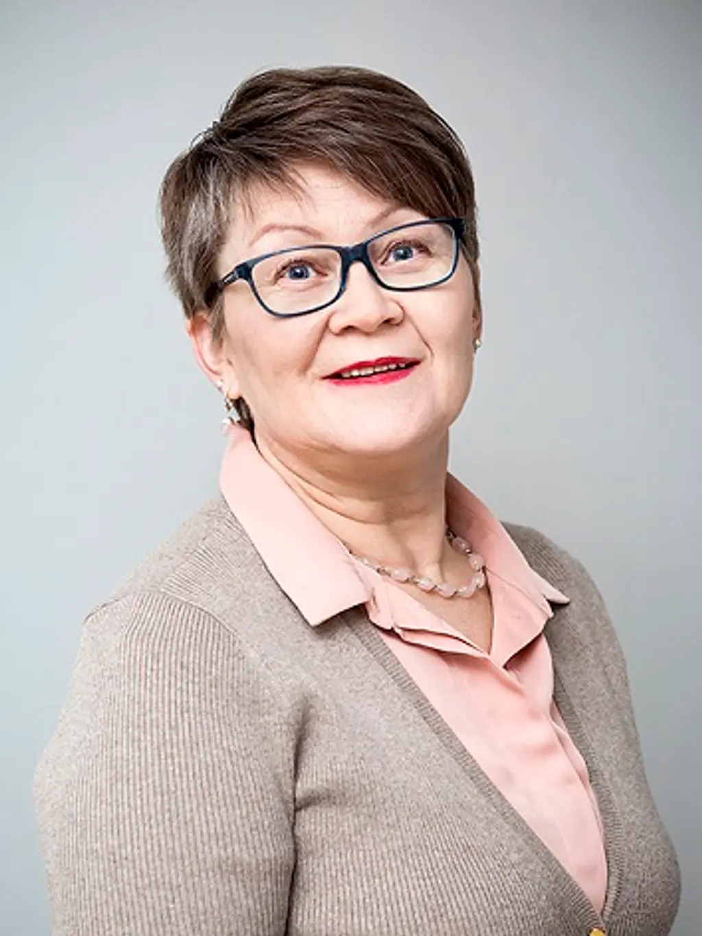 Nainen katsoo hymyillen kameraan
