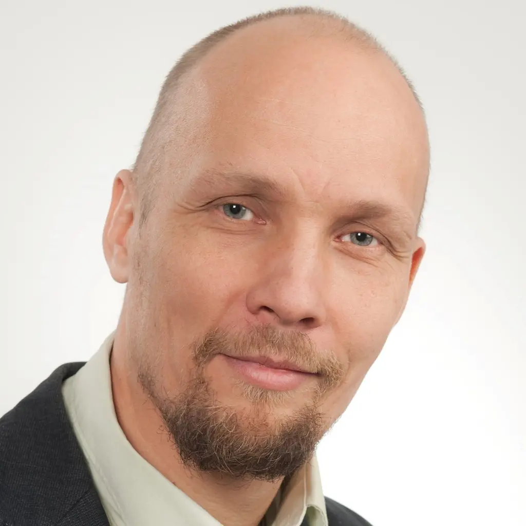 Mies katsoo kameraan hymyillen