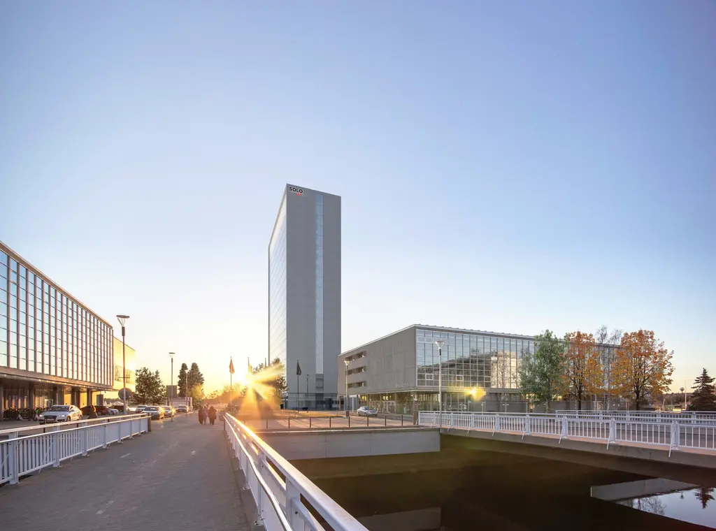 Kuva valoisasta arkkitehtuurimaisemasta, jossa näkyy moderneja rakennuksia ja silta.