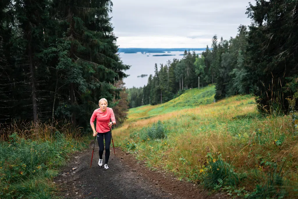 Ampumahiihtäjä Kaisa Mäkäräinen suorittamassa sauvarinnettä Kolin kesäisissä maisemissa