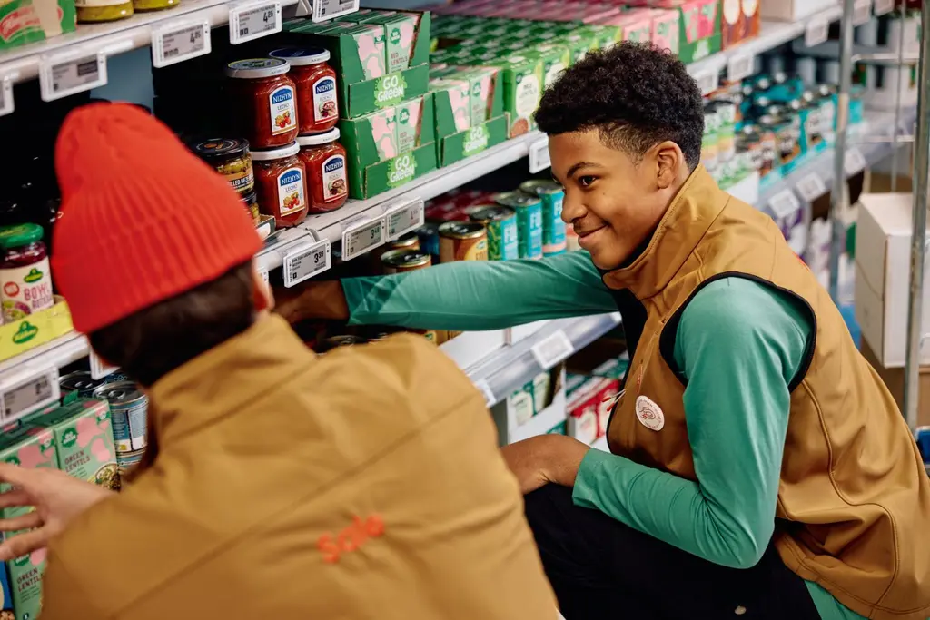 Kaksi myyjää hyllyttämässä tuotteita Salen työvaatteissa