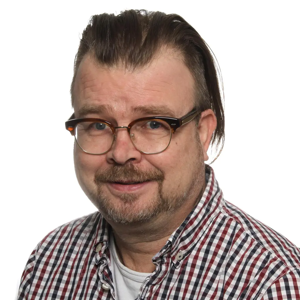 Mies katsoo kameraan hymyillen