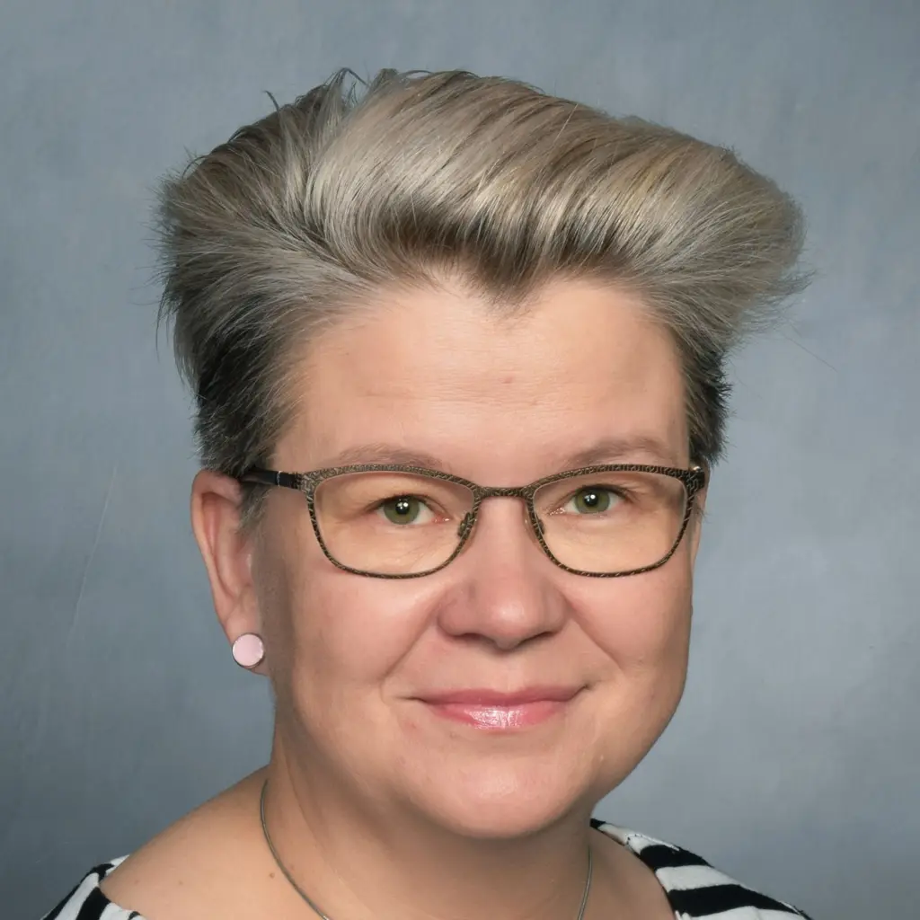 Nainen katsoo kameraan hymyillen
