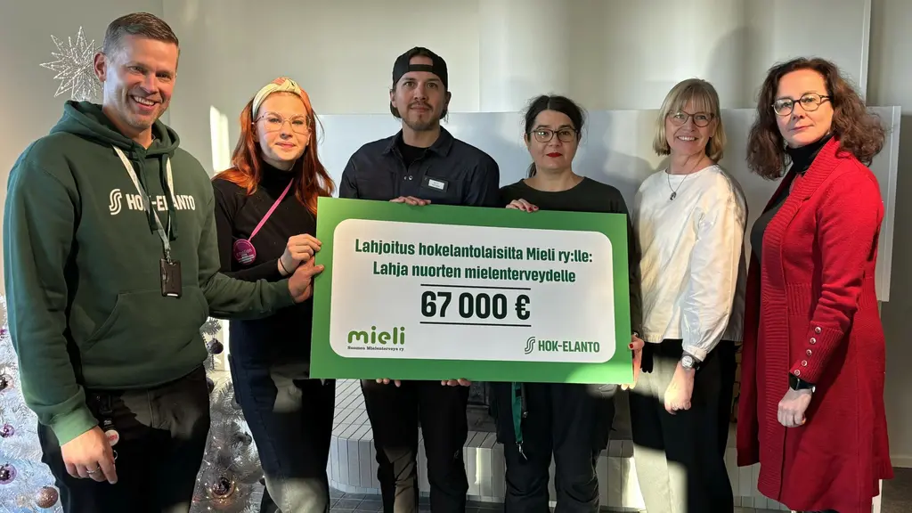 HOK-Elannon työntekijät ja Mieli ry:n työntekijät yhdessä lahjoitus julisteen kanssa.
