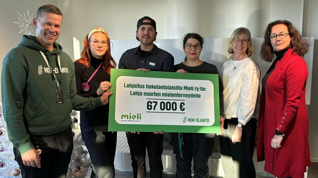 HOK-Elannon työntekijät ja Mieli ry:n työntekijät yhdessä lahjoitus julisteen kanssa.