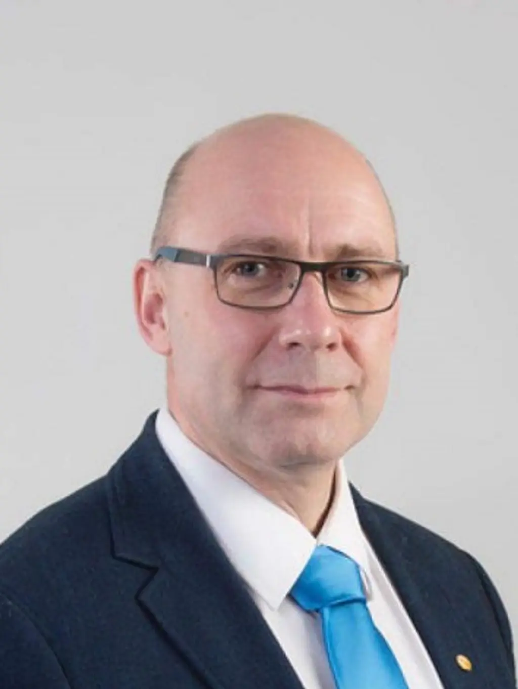 Mies katsoo kameraan hymyillen