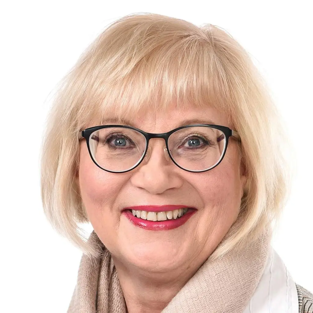 Nainen katsoo kameraan hymyillen.
