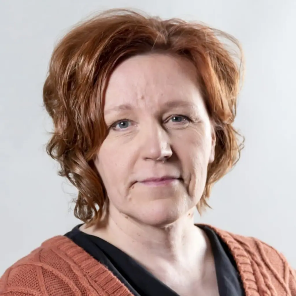 Nainen katsoo kameraan hymyillen