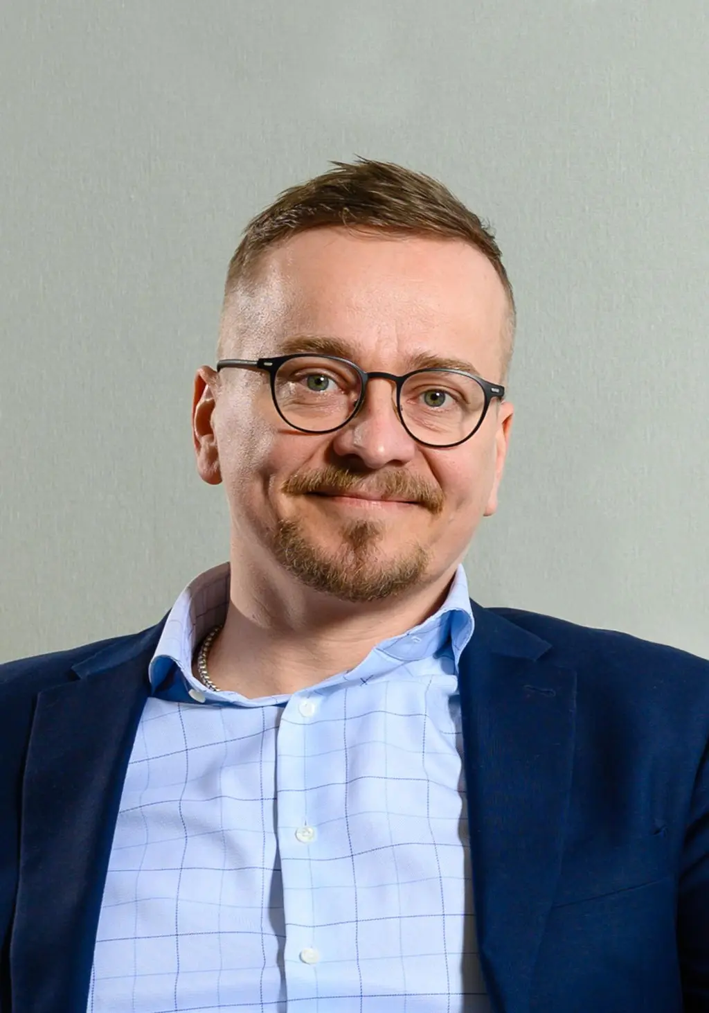 Mies katsoo kameraan hymyillen