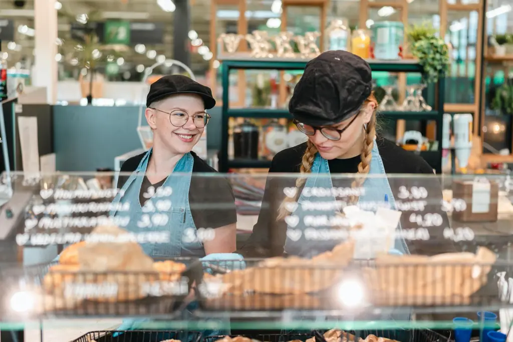 Kaksi kahvilatyöntekijää täyttää vitriiniä.