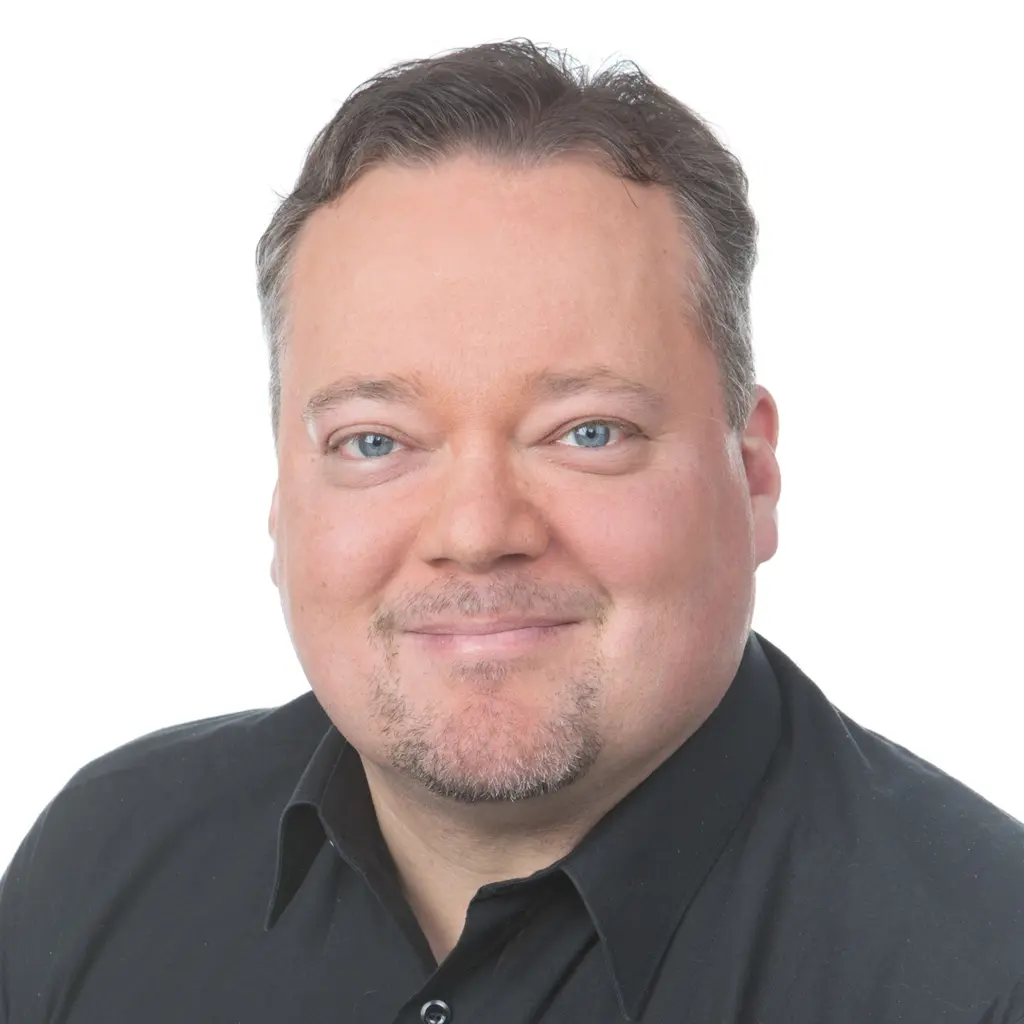 Mies katsoo kameraan hymyillen