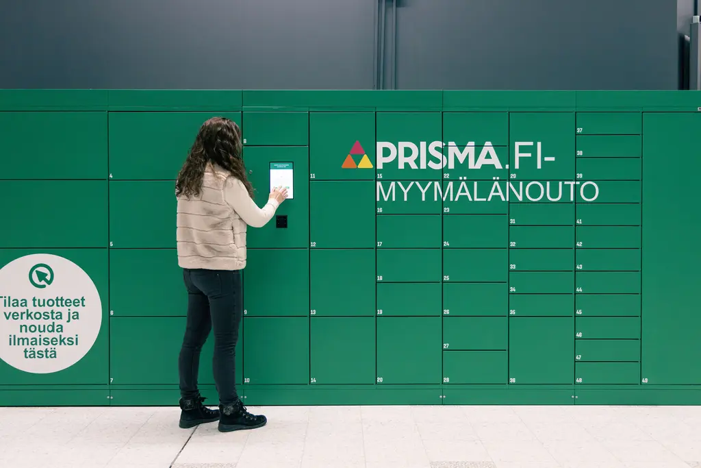 Asiakas seisoo vihreän noutolokerikon edessä.