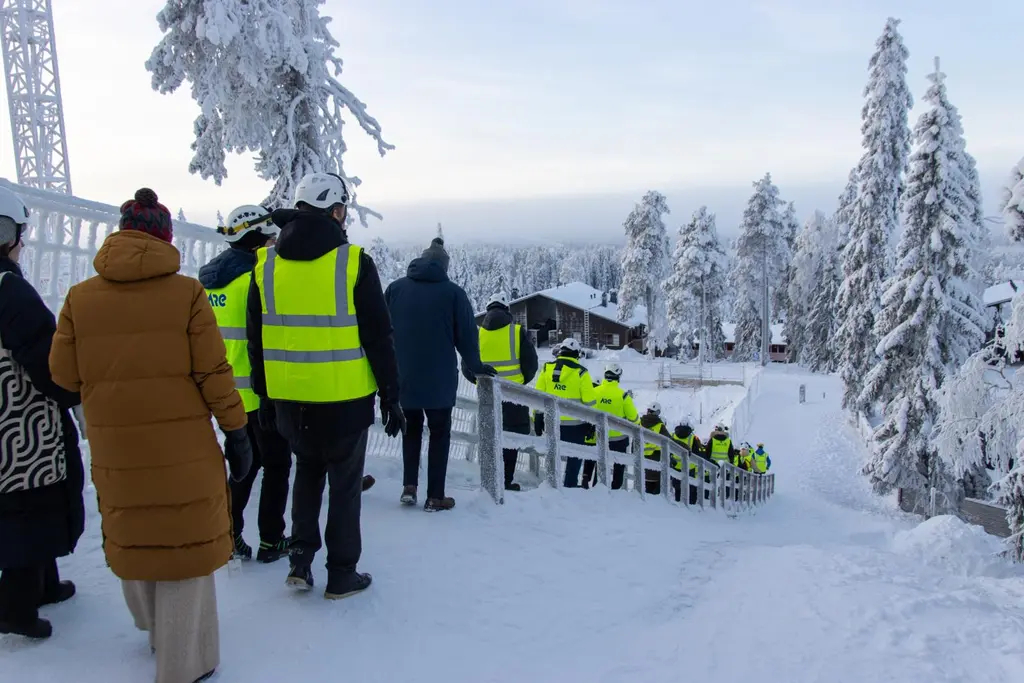 Ihmisiä laskeutumassa portaita työmaalle. Taustalla talvinen maisema.
