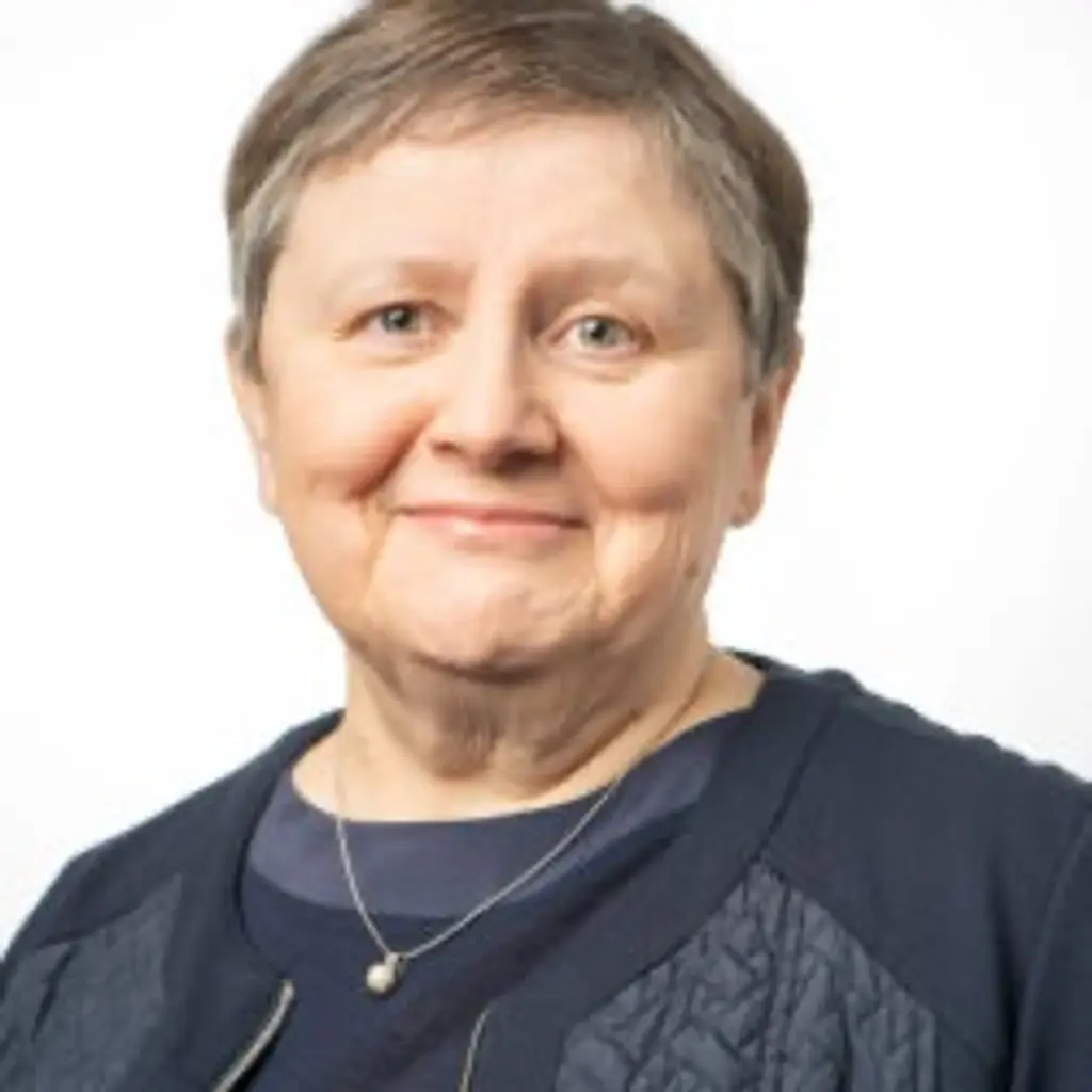 Nainen katsoo kameraan hymyillen