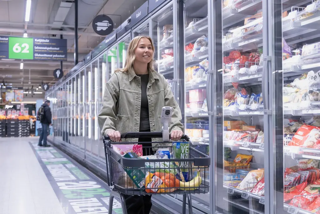 Asiakas ruokakaupassa kylmäkaappien edessä