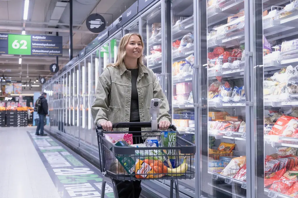Asiakas ruokakaupassa kylmäkaappien edessä