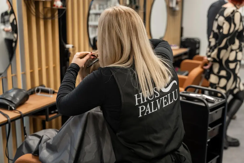 Hiuspalvelun kampaaja työn teossa.