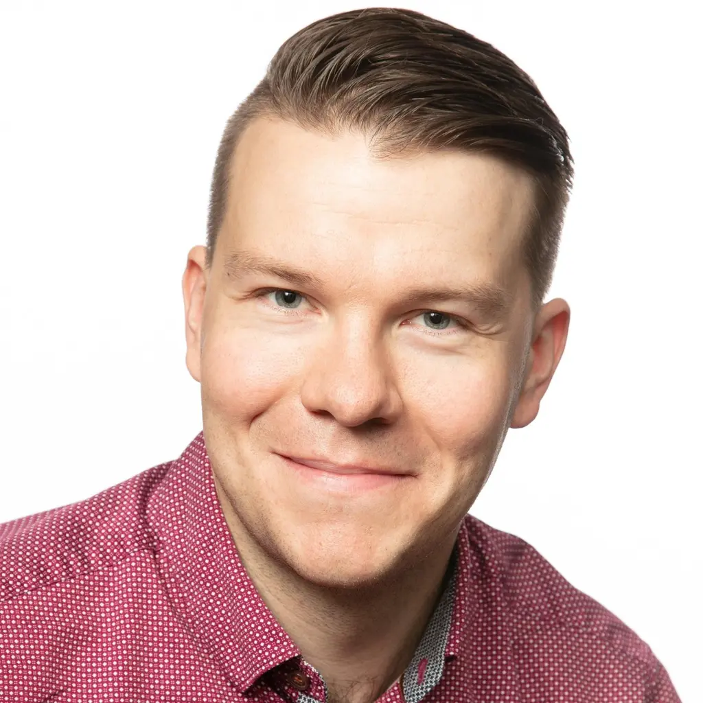 Mies katsoo kameraan hymyillen