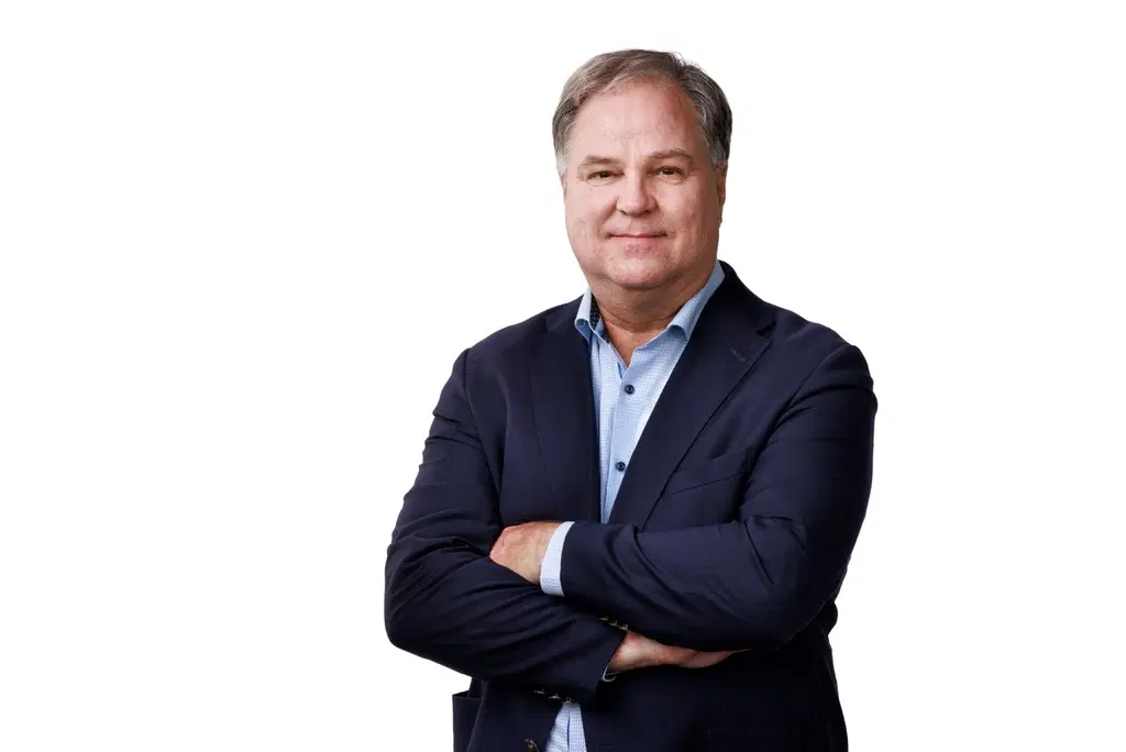 Mies katsoo kameraan hymyillen