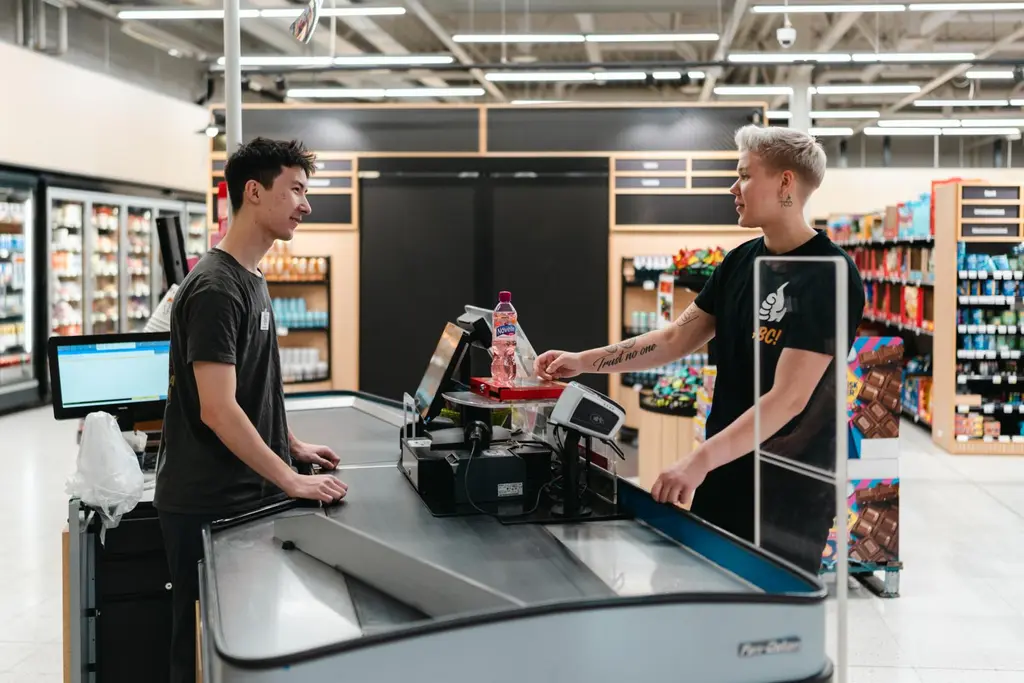 Kaksi ABC-työntekijää seisoo ABC Marketin kassalla.