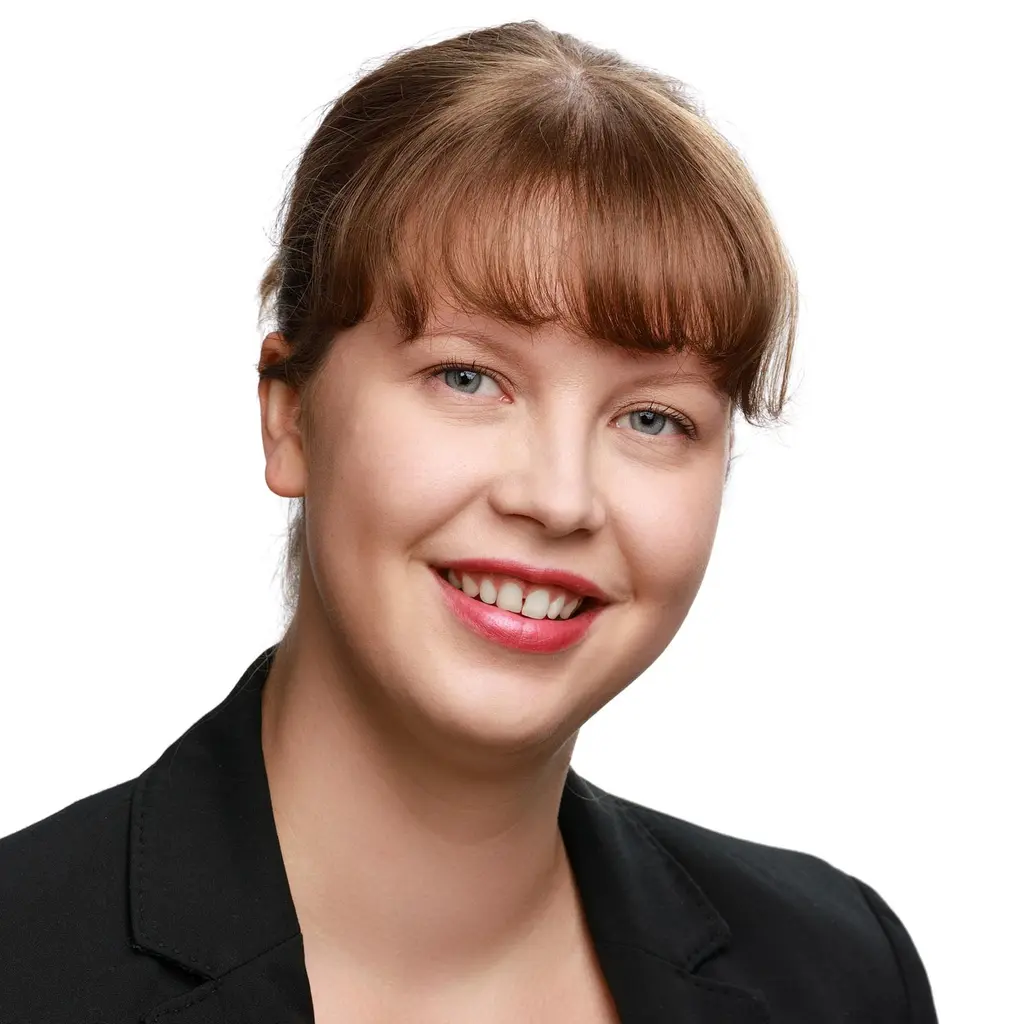 Nainen katsoo kameraan hymyillen