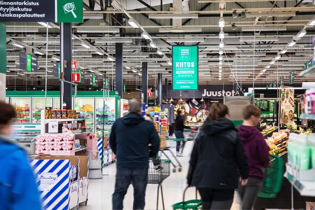 Asiakkaita Prismassa, mainostaulu katossa