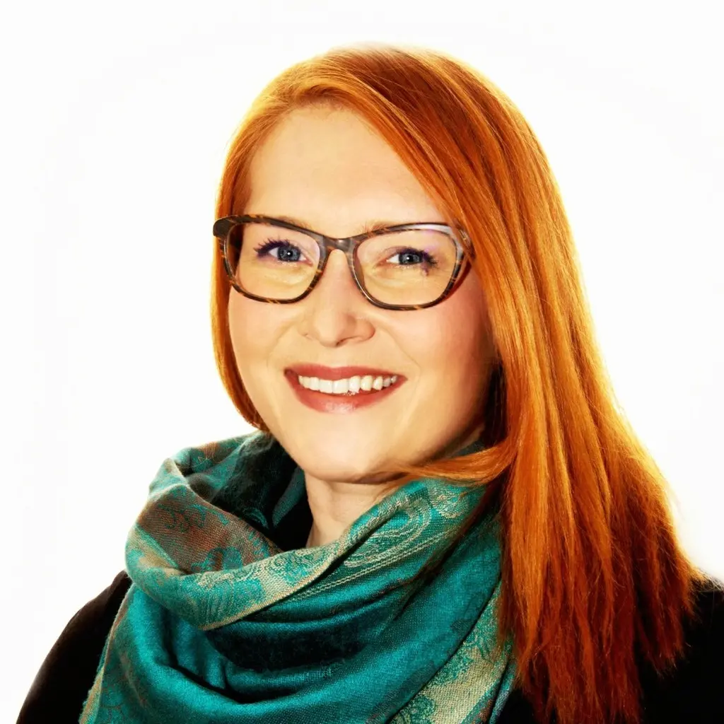 Nainen katsoo kameraan hymyillen