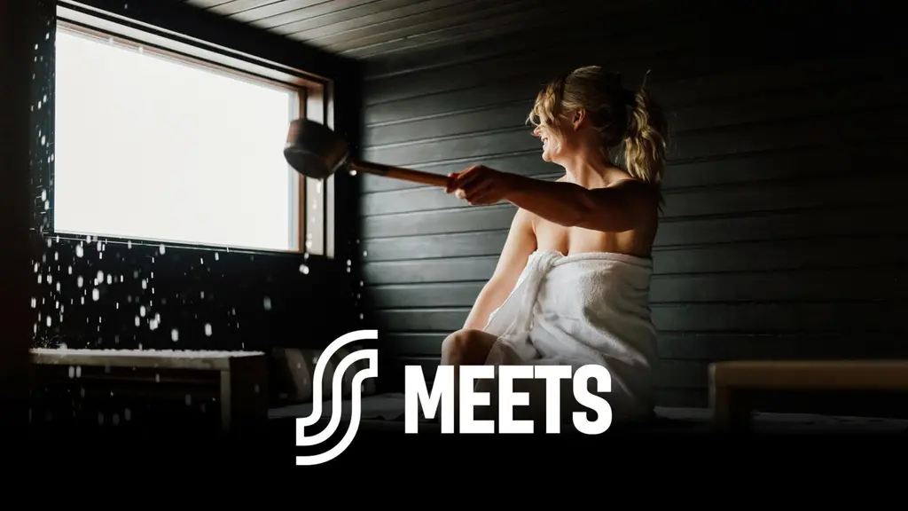 Nainen heittää löylyä kiukaalle saunassa.