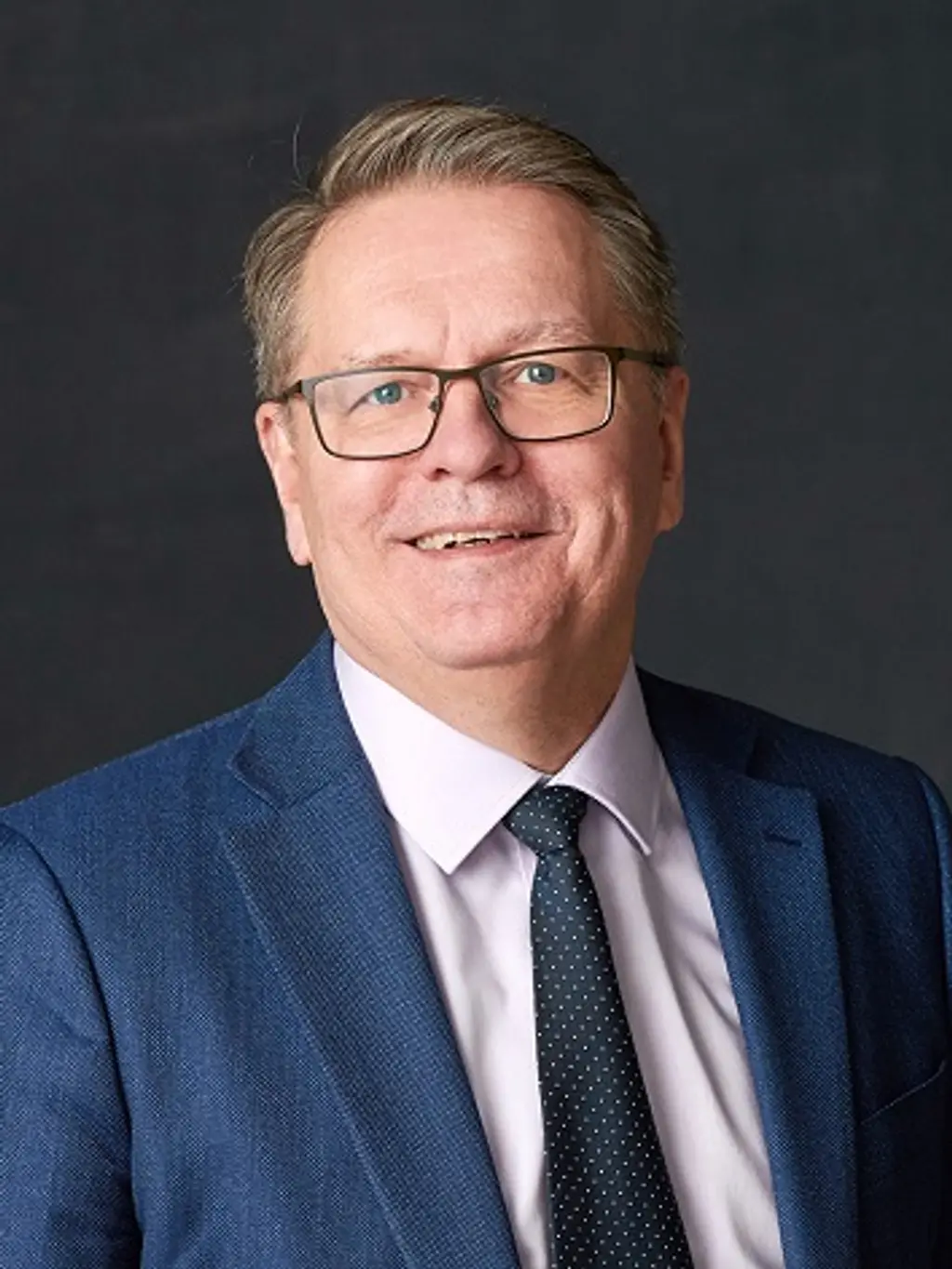 Mies katsoo kameraan hymyillen
