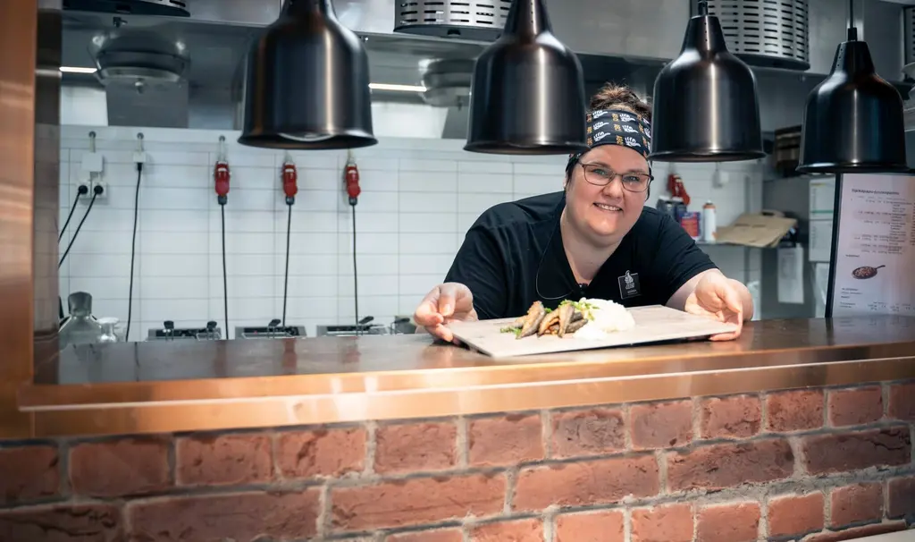 Kokki asettaa valmiin ruoka-annoksen lämpölamppujen alle.