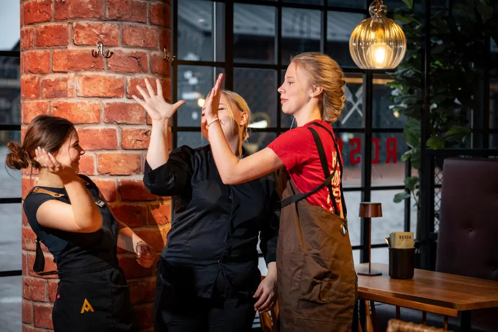 Kolme Rosson työntekijää heittävät keskenään hymyillen ylävitoset.