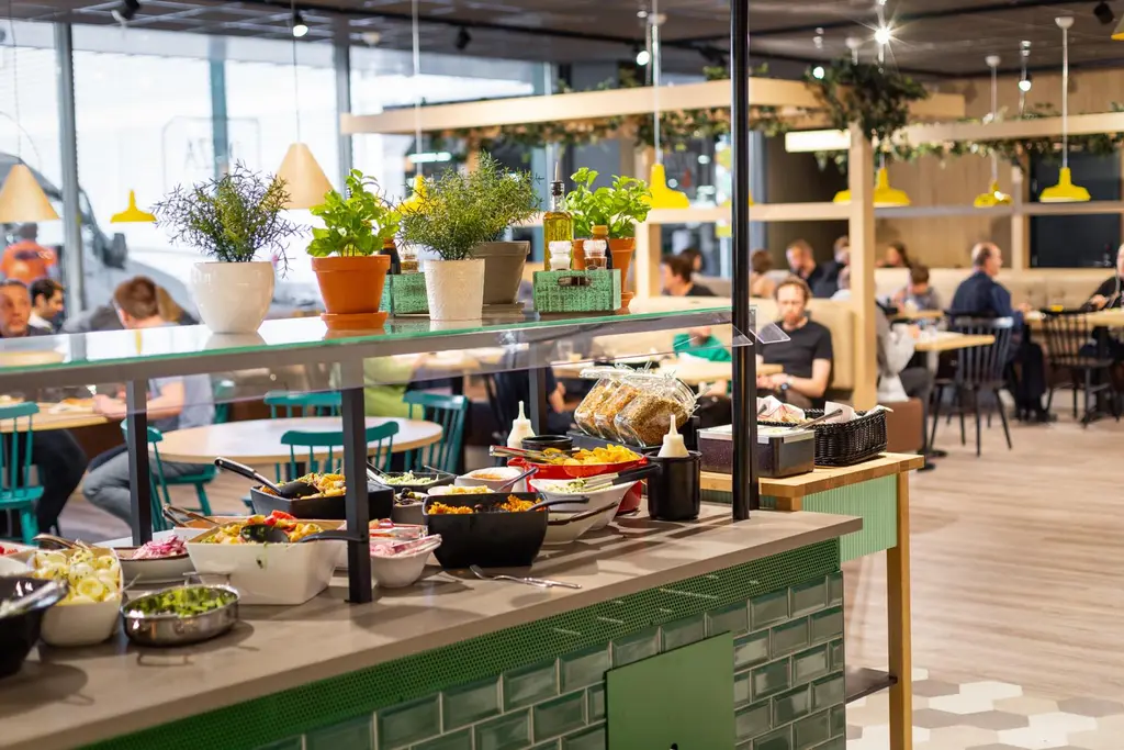 Näkymä ravintolasaliin, etualalla noutopöytä, jossa erilaisia salaatteja.