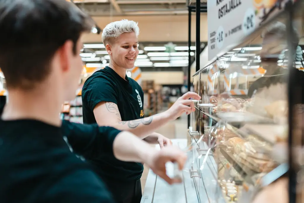 Kaksi ABC-työntekijää täyttää liikenneaseman vitriinejä.