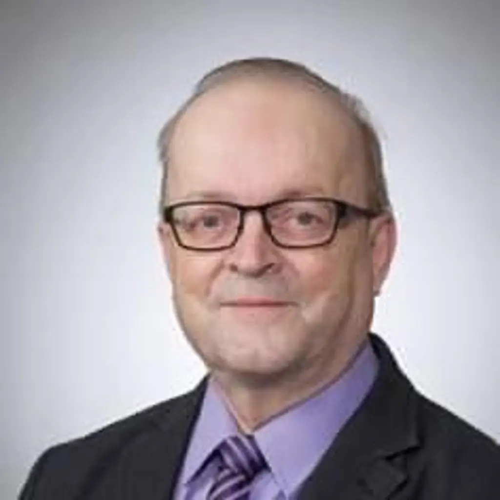 Mies katsoo kameraan hymyillen