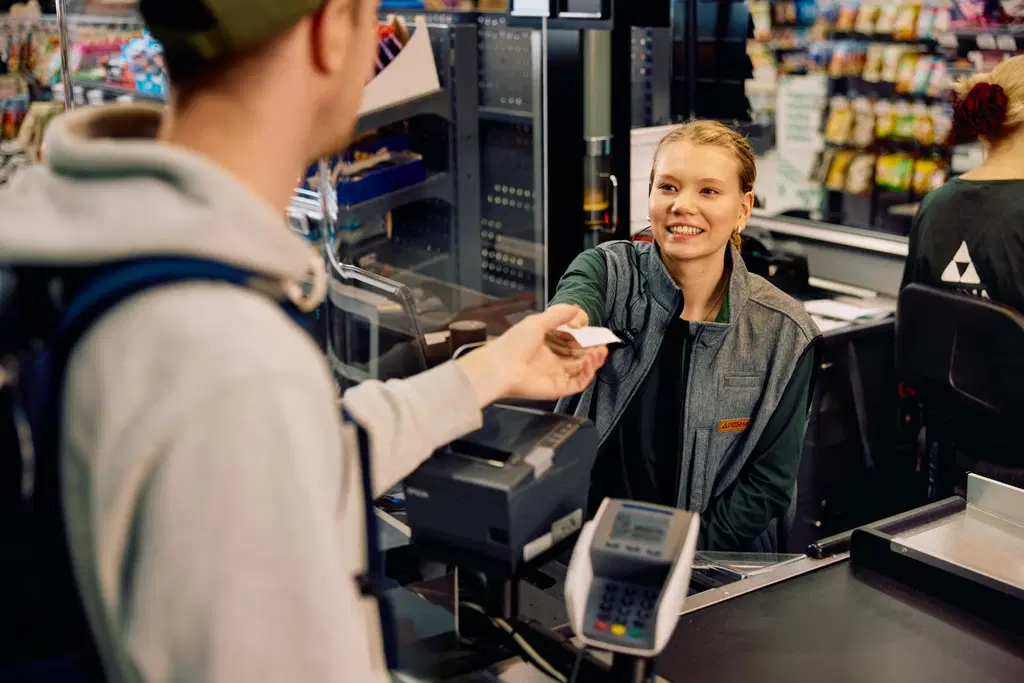 Kassatyöntekijä ojentaa kuittia asiakkaalle.