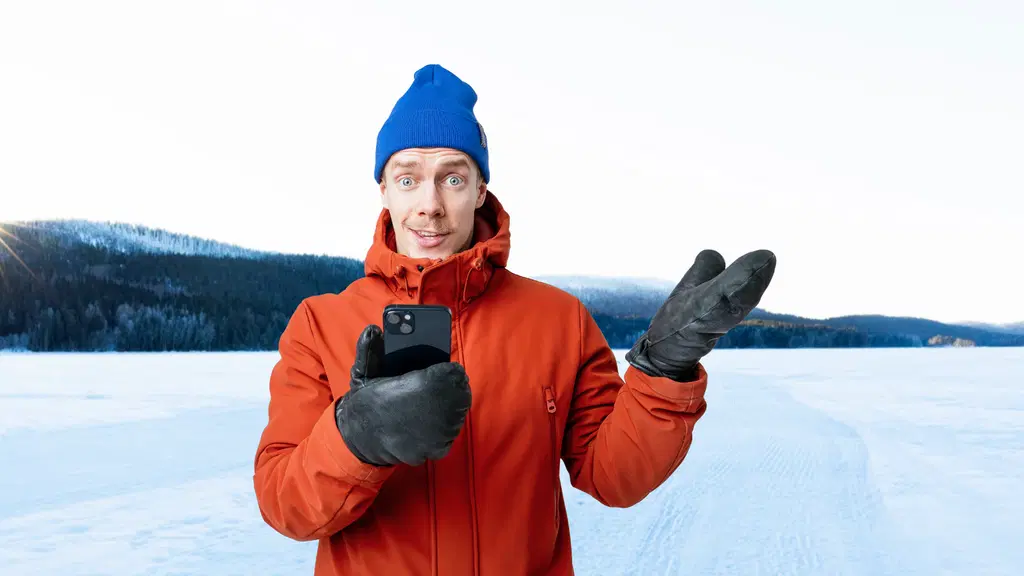 Kalle seisoo talvisessa maisemassa talvitamineet päällä puhelin kädessä