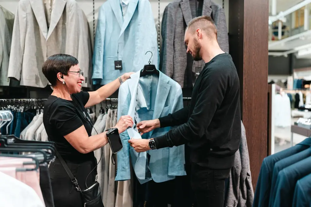 Sokoksen työntekijä esittelee asiakkaalle puvuntakkia.