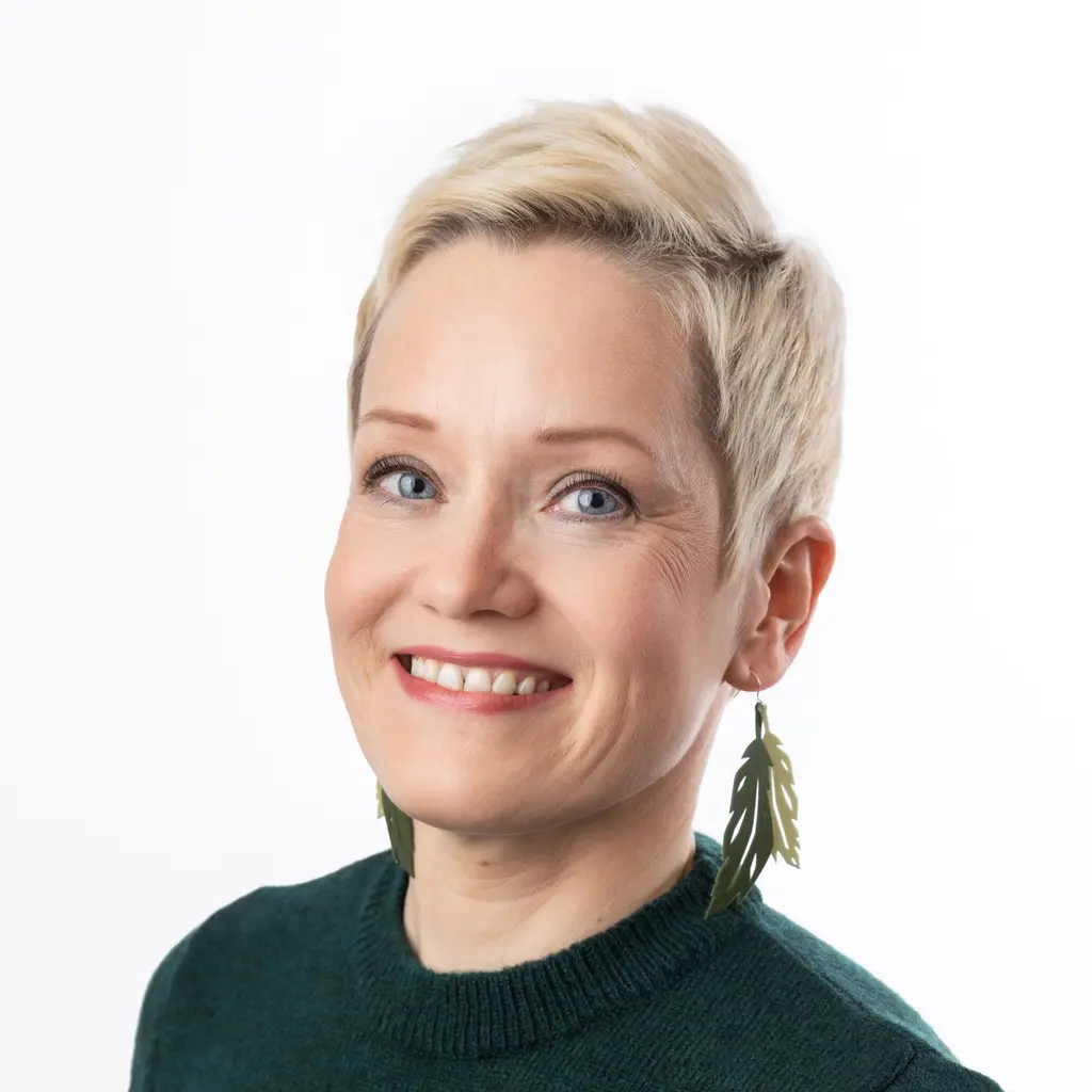 Nainen katsoo kameraan hymyillen
