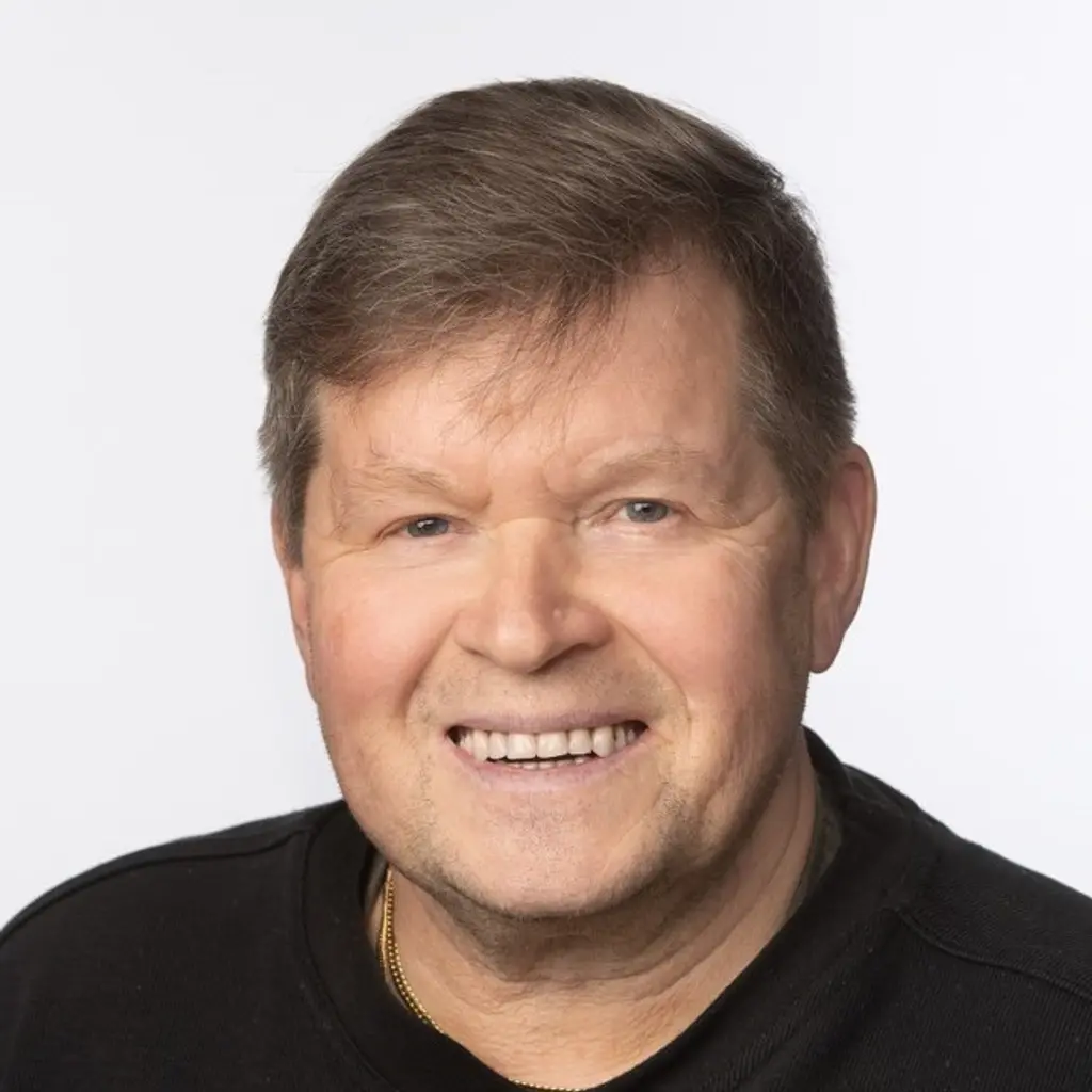 Mies katsoo kameraan hymyillen