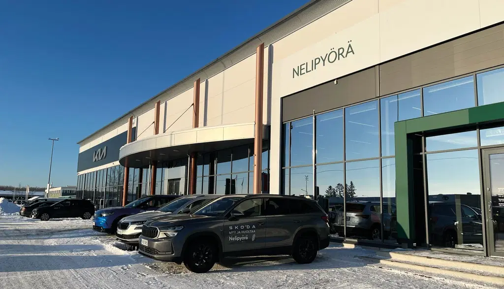 Nelipyörä-autokauppa talvella. Rakennuksen edessä rivi autoja.