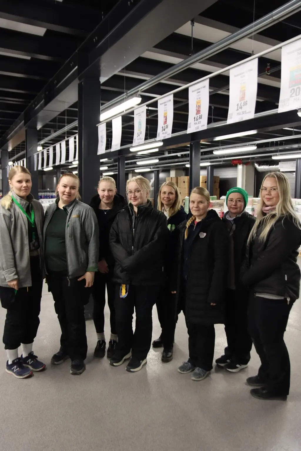 Kahdeksan naista katsoo kameraan hymyillen.